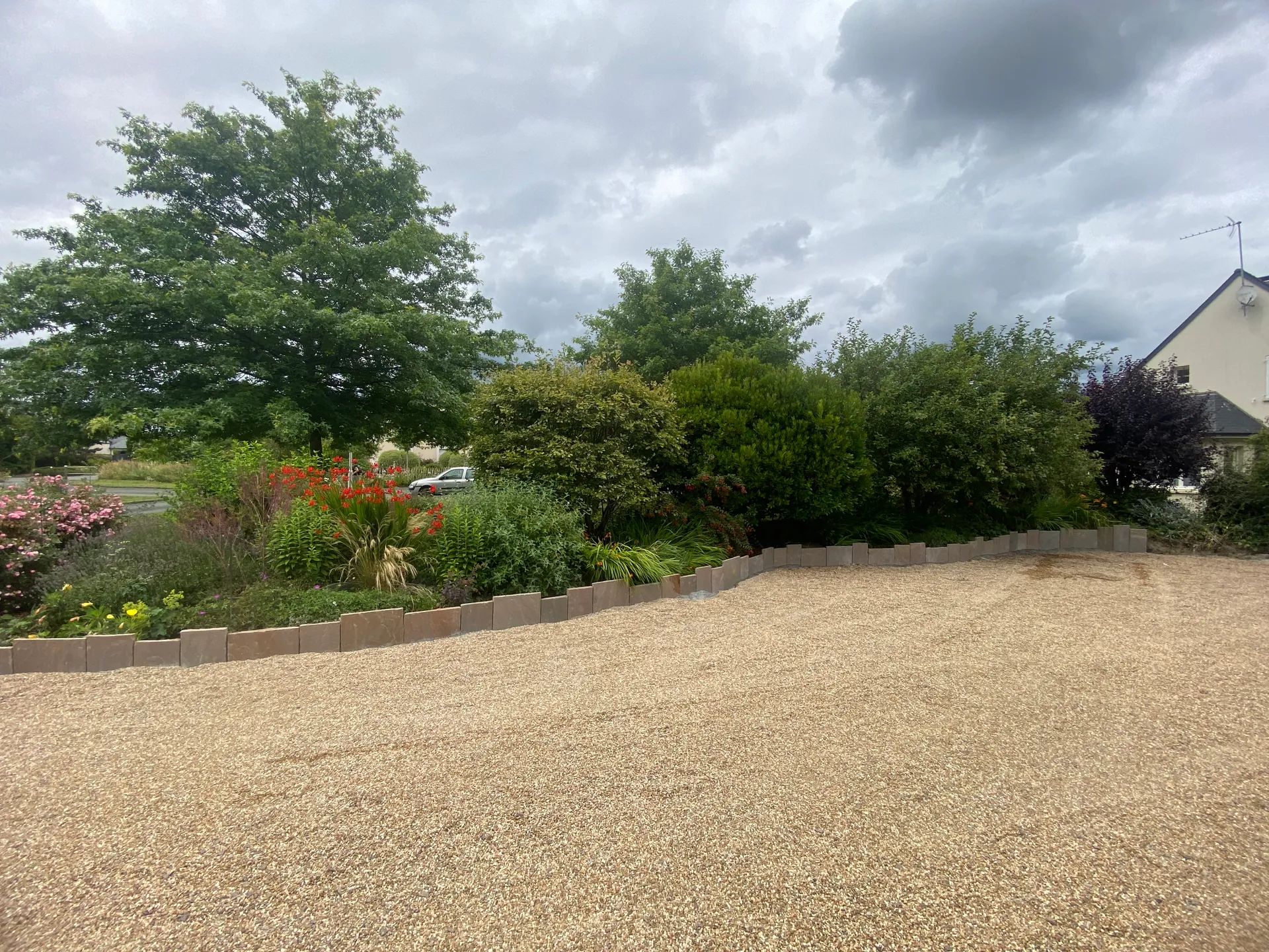 Amenagement paysager complet avec allee en gravillon et massifs vegetaux