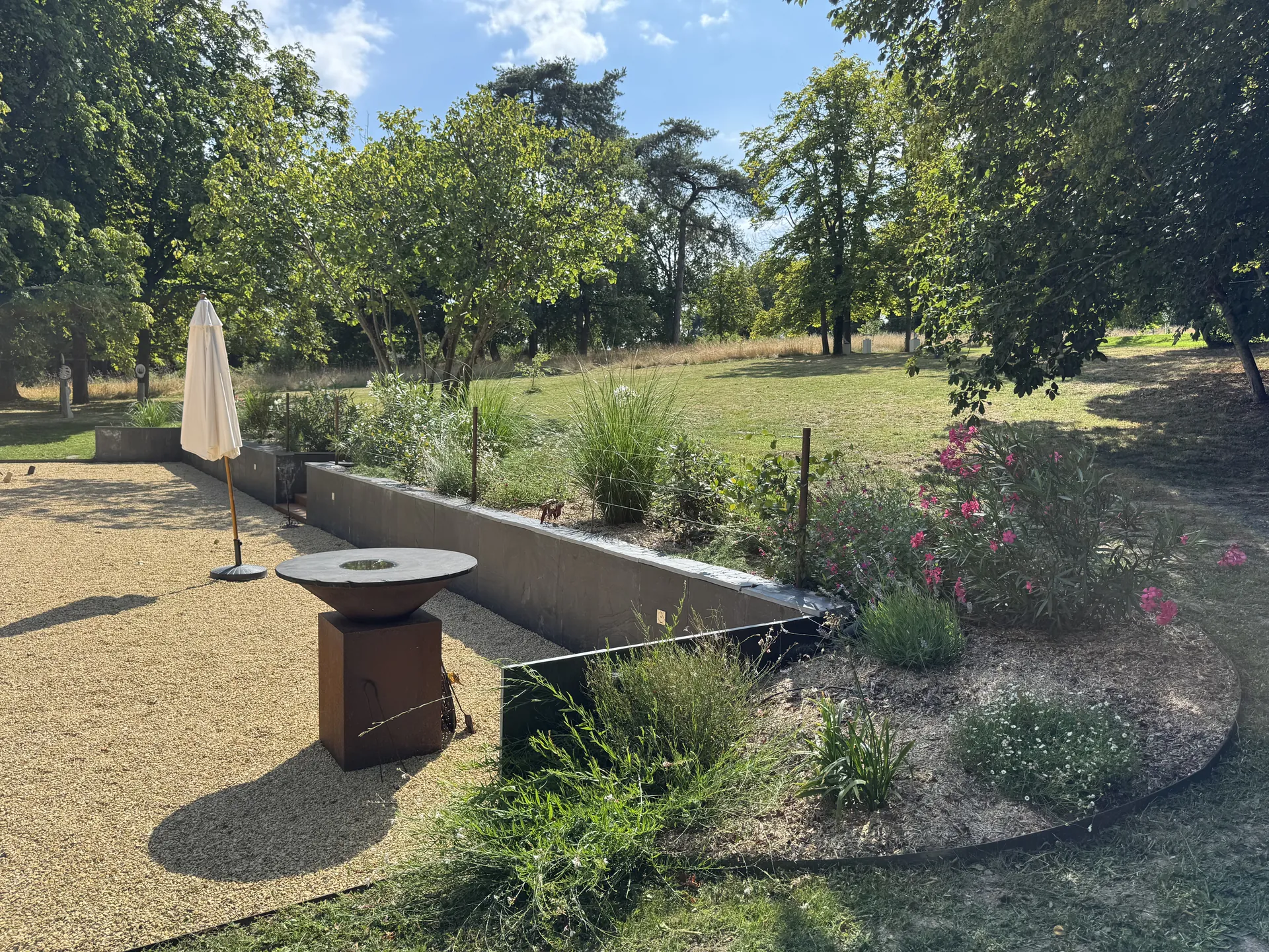 Terrasse en gravier stabilise avec muret en acier corten et massifs fleuris - paysagiste Angers